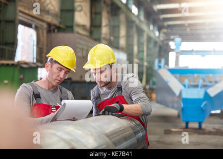 Travailleurs masculins avec presse-papiers en usine Banque D'Images