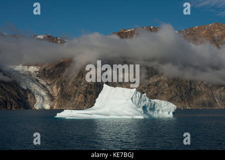 Groenland, Scoresbysund Aka Scoresby Sund, Nordvestfjord. D'immenses icebergs flottant dans un fjord calme devant le glacier qui s'est déreculé. Banque D'Images