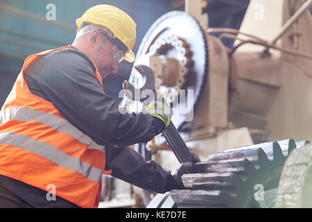 Homme utilisant une grande clé sur une pince en usine Banque D'Images