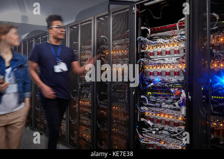 Les techniciens INFORMATIQUES se promexécutant le long des panneaux dans la salle des serveurs Banque D'Images