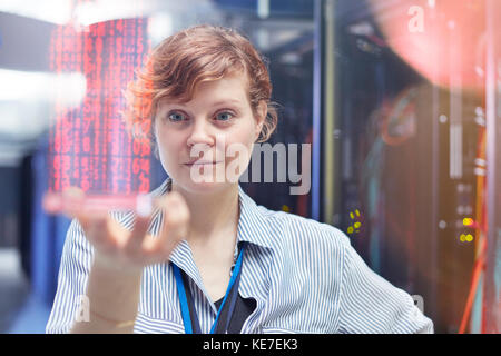 Femme TECHNICIENNE informatique tenant une tablette numérique futuriste dans la salle des serveurs Banque D'Images