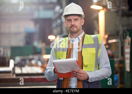 Contremaître homme confiant en portrait avec presse-papiers en usine Banque D'Images