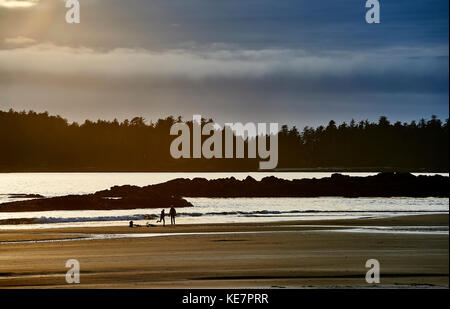 Silhouette d'un couple et leurs vélos sur la plage Mackenzie au coucher du soleil ; Tofino, Colombie-Britannique, Canada Banque D'Images