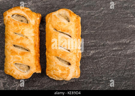 Rouleaux de saucisses en croûte noire sur une tuile ardoise cuisine with copy space Banque D'Images