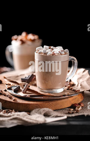 La composition avec deux verre de cappuccino surmonté de guimauve et servi avec des grains de café et chocolat sur planche en bois noir sur zone Banque D'Images