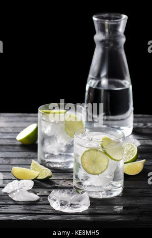 Selective focus la composition avec gin tonic cocktail servis avec des agrumes sur table en bois avec des morceaux de glace Banque D'Images