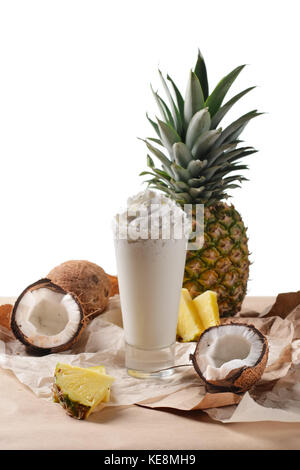 Composition au point sélective avec cocktail de noix de coco servi avec de l'ananas et noix de coco sur un papier sur la table en bois Banque D'Images