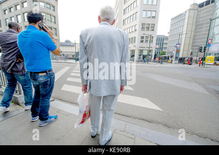 Bruxelles, Belgique. Homme dans un costume blanc en attendant de traverser la route Banque D'Images