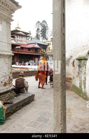 Repetto Noémie / Le pictorium - Népal - Katmandou. temple de Pashupatinath. patrimoine mondial depuis 1979. - 20/09/2017 - Népal Katmandou / / Kathmandu - Népal - KATMANDOU. Le temple de Pashupatinath. patrimoine mondial de l'humanité depuis 1979. Un homme représente shiva en forme humaine et se déplace sur le site du temple. Il porte une couronne de fleurs et le corps peint en orange en conformité avec la statue illustrant shiva, situé à l'entrée du site. Banque D'Images