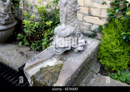 Dragon chinois en béton ou de poisson staute fontaine à l'eau dans un jardin ornemental au Royaume-Uni Banque D'Images