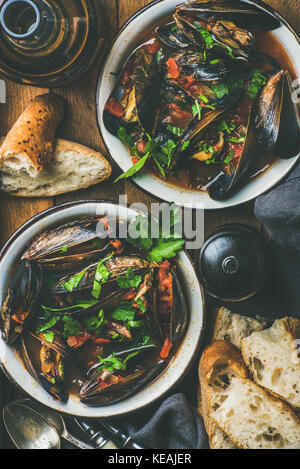 Les moules cuites à la sauce tomate et la bière sur fond rustique Banque D'Images