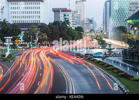 Trafic, capturé avec blurred motion, se précipite le long de l'avenue Thamrin au coeur de quartier du centre-ville de Jakarta en Indonésie capitale dans la nuit. Banque D'Images