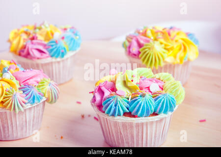 Cupcake fait maison avec de la crème et les baies, décoré de crème délicieux et décorations colorées, se tenir dans une ligne sur un tableau blanc Banque D'Images