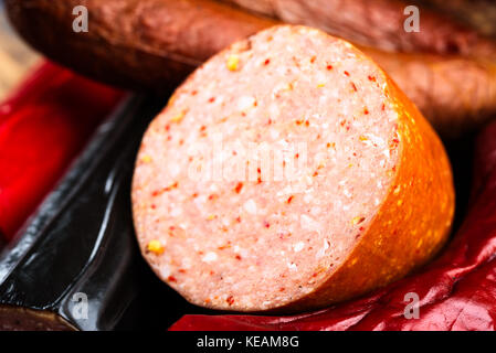 Délicieux morceau de saucisse fumée reposant sur d'autres saucisses dans l'arrière-plan. Ouvrir la surface de tranches de viande et d'épices montrer. Banque D'Images