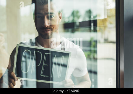 Waiter holding chalkboard with open word