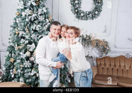 Portrait de jeune famille accueillante looking at camera le matin de Noël. père, mère et fille Banque D'Images