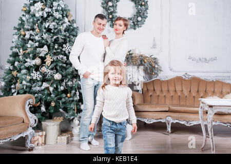 Portrait de jeune famille accueillante looking at camera le matin de Noël. père, mère et fille Banque D'Images