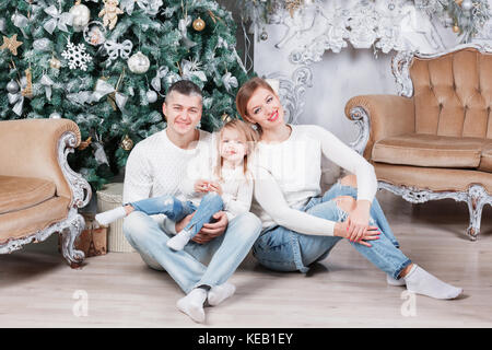 Portrait de jeune famille accueillante looking at camera le matin de Noël. père, mère et fille Banque D'Images