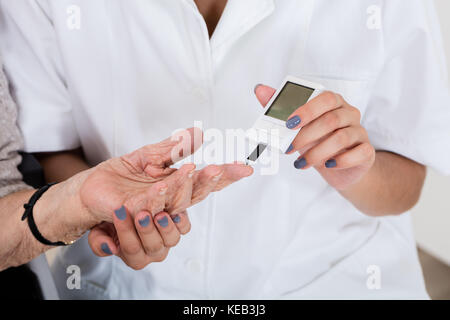 Close-up of doctor holding doigt du patient Vérification du niveau de sucre avec diabete Banque D'Images