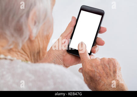 Close-up of Senior Woman Using Smartphone avec écran vide à la maison Banque D'Images