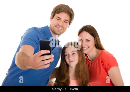 Smiling young parent prendre avec leur fille selfies on cellphone Banque D'Images