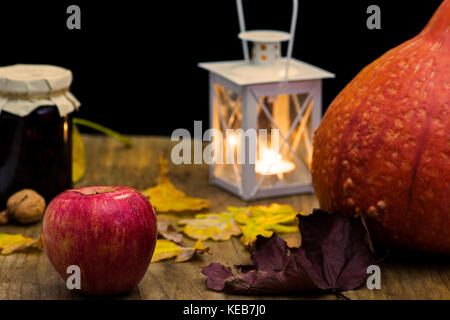 La vie encore automne sombre avec la citrouille, bougie et lampe, avec feuilles jaunes des arbres sur la vieille table en bois - atmosphère avec des couleurs chaudes Banque D'Images