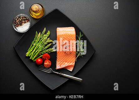 Steak de saumon cru avec des ingrédients frais sur fond noir Banque D'Images