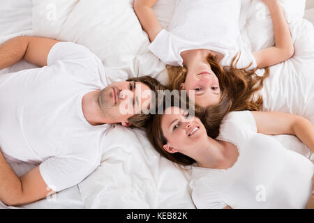 High Angle View Of A Happy Family Lying On Bed Banque D'Images