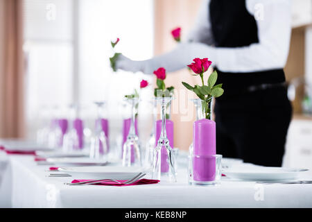 Close-up of Waiter Organiser Roses dans vase sur la table de Mariage Banque D'Images