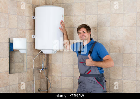 Portrait of smiling technician gesturing Thumbs up dans la salle de bains Banque D'Images