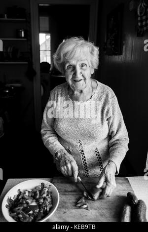 Une femme âgée dans la cuisine légumes côtelettes de salade. photo en noir et blanc. Banque D'Images