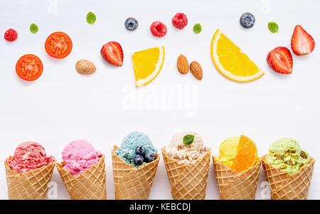 Divers de crème glacée à saveur de bleuets cônes fraise, pistache, amande, orange, cerise et de configuration à l'arrière-plan en bois blanc et doux m'été . Banque D'Images