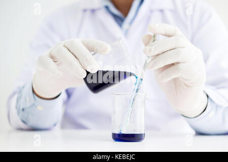 Les scientifiques et le matériel scientifique, verser le mélange liqiud réactifs de laboratoire chimie,bécher recherche concept Banque D'Images