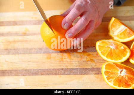 Un homme coupe orange sanguine sur une planche à découper, place pour le texte Banque D'Images