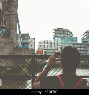 Un touriste prend une photo de Tower Bridge sur son téléphone portable Banque D'Images