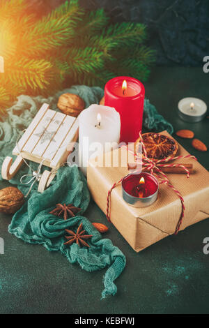 De Noël et du nouvel an, des bougies allumées avec un cadeau dans du papier kraft, branches d'épinette, les oranges et les épices Banque D'Images