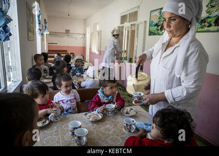 Beshkent, Kirghizistan. 11 octobre 2016. Turdenisa Khydyraieva fournit de l’eau bouillie et des biscuits aux enfants dans un jardin d’enfants de Beshkent, au Kirghizistan, où l’eau est recueillie à partir d’un canal d’irrigation appelé aryk. L'approvisionnement local en eau est vulnérable à la contamination par les bactéries qui causent l'hépatite et d'autres maladies d'origine hydrique. Les habitants espèrent et planifient un projet d'infrastructure pour apporter de l'eau potable à leurs maisons. Dans les villages à travers le Kirghizistan (Asie centrale), les systèmes et infrastructures obsolètes de distribution d'eau sont la cause de problèmes de santé tels que les épidémies d'hépatite et Banque D'Images