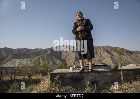 Beshkent, Kirghizistan. 12 octobre 2016. Cumagul Tolukbaeva, directrice d’école primaire, se dresse au sommet d’un réservoir d’eau utilisé dans le village de Lyaily, où elle vit avec sa famille. Quelques maisons et l'école et le jardin d'enfants locaux sont servis avec une petite quantité d'eau de source qui coule vers le bas d'une source au-dessus du village. Le reste des 300 familles dépendent de l'eau d'un canal d'irrigation appelé aryk qui est sensible à la contamination. Dans les villages du Kirghizistan (Asie centrale), les systèmes et infrastructures obsolètes de distribution d'eau sont à l'origine de problèmes de santé tels que Banque D'Images