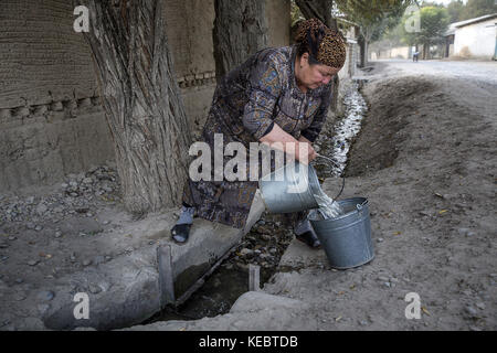 Beshkent, Kirghizistan. 12 octobre 2016. Anabar Nosirova, une ouvrière de cuisine à l'école du village de Beshkent, recueille l'eau d'un arret voisin, qu'elle filtre à travers le tissu et laisse reposer la nuit pour que la poussière se dépose au fond. Le lendemain matin, elle fait bouillir l'eau avant de préparer le thé pour les étudiants. Les habitants espèrent et planifient un projet d'infrastructure pour apporter de l'eau potable à leurs maisons, écoles et installations médicales. Dans les villages à travers le Kirghizistan (Asie centrale), les systèmes et infrastructures obsolètes de distribution d'eau sont la cause de problèmes de santé tels que les épidémies de Banque D'Images