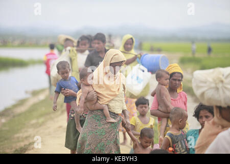 Ukhiya, Cox's Bazar, Bangladesh. 19 octobre 2017. Les musulmans rohingyas, qui ont passé quatre jours à l'air libre après avoir traversé le Myanmar au Bangladesh, portent leurs enfants et leurs effets personnels après avoir été autorisés à se rendre dans un camp de réfugiés, à Anjuman para, Ukhiya, Bangladesh, le 19 octobre, plus de 2017 580 000 réfugiés sont arrivés au Bangladesh depuis le mois d'août 25, date à laquelle les forces de sécurité du Myanmar ont lancé une campagne de terre brûlée contre les villages rohingyas. Crédit : ZUMA Press, Inc/Alamy Live News Banque D'Images