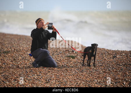 Hastings, East Sussex, UK. 20 octobre 2017. Très ensoleillée, avec rafales de vent, les conditions de vitesse 25km/h et des rafales allant jusqu'à 41 mph. Cet homme et son chien de prendre un moment pour une photo, alors que les mers font rage dans l'arrière-plan. Prévision est pour un temps orageux pour la fin de semaine. Crédit photo : Paul Lawrenson /Alamy Live News Banque D'Images