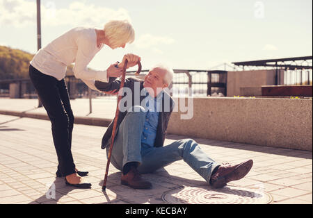 Caring woman offrant de l'aide d'un homme déchu Banque D'Images