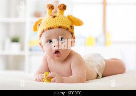 Adorable bébé garçon couché sur le ventre et chapeau portés par... Banque D'Images