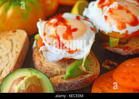 Oeufs frits garnis de sauce chili chaud sur toast à l'avocat Banque D'Images
