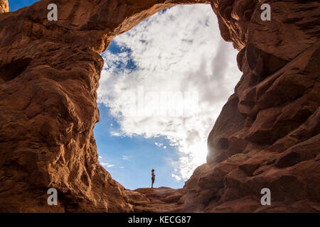 En femme debout dans la tourelle du rétroéclairage arch dans le Arches national park, Utah, USA Banque D'Images