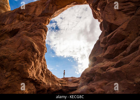 En femme debout dans la tourelle du rétroéclairage arch dans le Arches national park, Utah, USA Banque D'Images