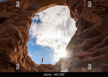 En femme debout dans la tourelle du rétroéclairage arch dans le Arches national park, Utah, USA Banque D'Images