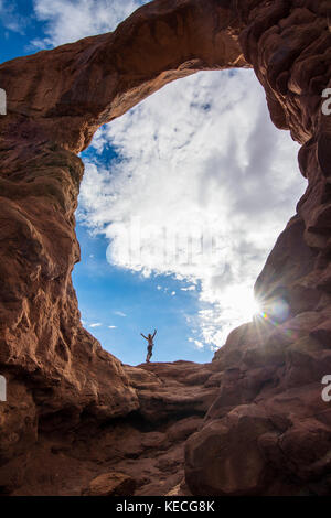 En femme debout dans la tourelle du rétroéclairage arch dans le Arches national park, Utah, USA Banque D'Images