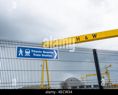 Panneau indiquant la gare du quartier Titanic. Les grues de chantier géants Samson et Goliath peuvent être vues en arrière-plan Banque D'Images