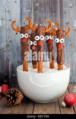 Le renne de noël mignon tiges bretzel au chocolat dans un bol avec un vieux fond de bois gris Banque D'Images